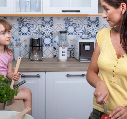 A mother and daughter enjoy cooking together in a cozy modern kitchen, fostering family bonds.