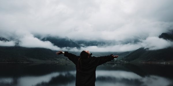 A person enjoys a sense of freedom by a misty mountain lake, embracing nature's tranquility.