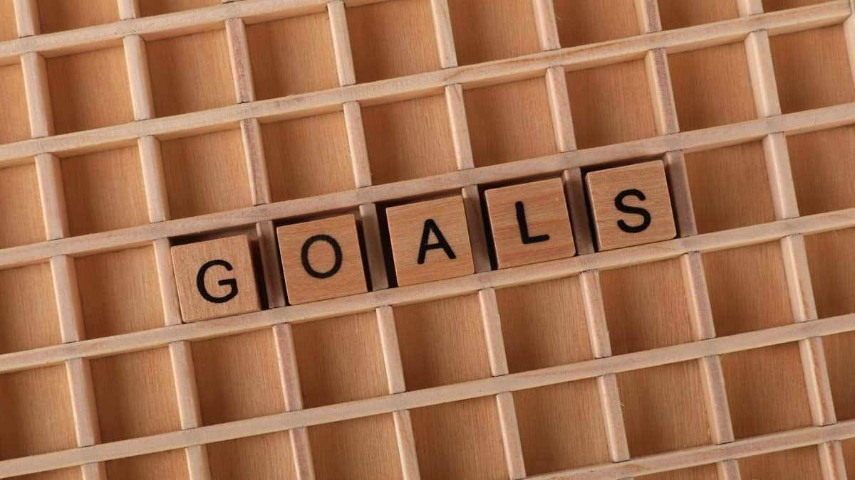Wooden blocks spelling the word 'Goals' arranged on a wooden grid, symbolizing planning and achievement.